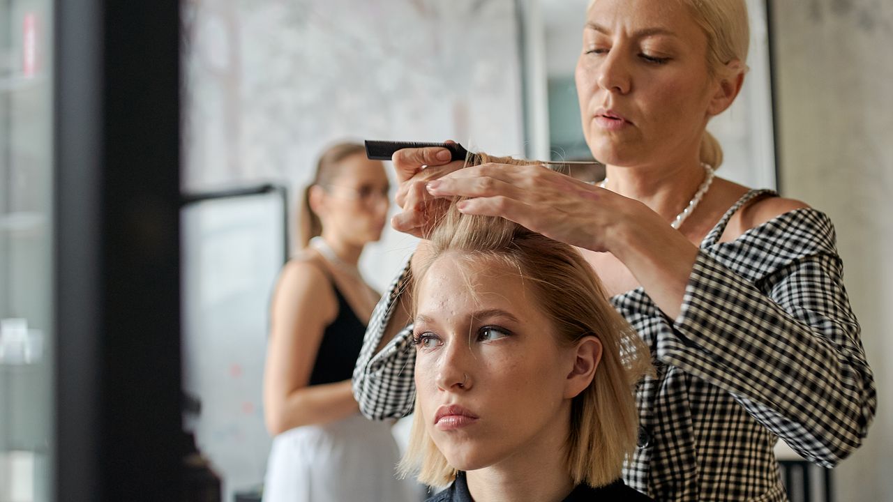 Frisør styler håret til en kunde i salongen
